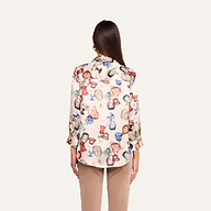 A person stands facing away, wearing a Dani Silk Blouse featuring a vintage glassware print and light brown pants against a plain, light background.