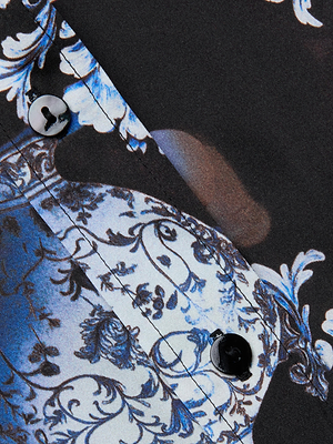 Close-up of the Dani Silk Blouse by L'AGENCE, crafted from silk charmeuse with a blue and white floral ornate pattern and two black buttons—an elegant choice for a luxurious three-quarter sleeve shirt.