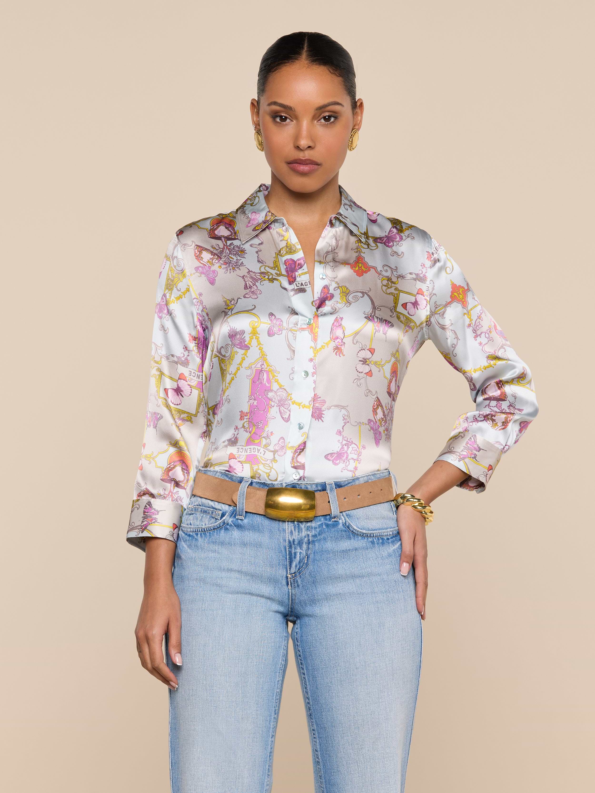 A woman wearing the Dani Silk Blouse paired with light blue jeans and a beige belt stands against a plain light background, looking directly at the camera with a neutral expression.