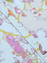 Close-up of the Dani Silk Blouse, a light blue patterned silk button-down shirt with shiny buttons, adorned with pink, purple, and yellow ornate designs featuring butterflies and decorative baroque toile print motifs.
