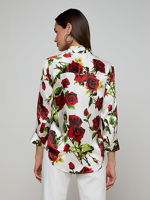 A woman wearing the Dani Silk Blouse featuring a vibrant red rose print.