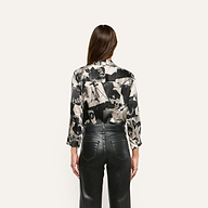 Back view of the Dani Silk Blouse in a black-and-white collage print, tucked into black pants.