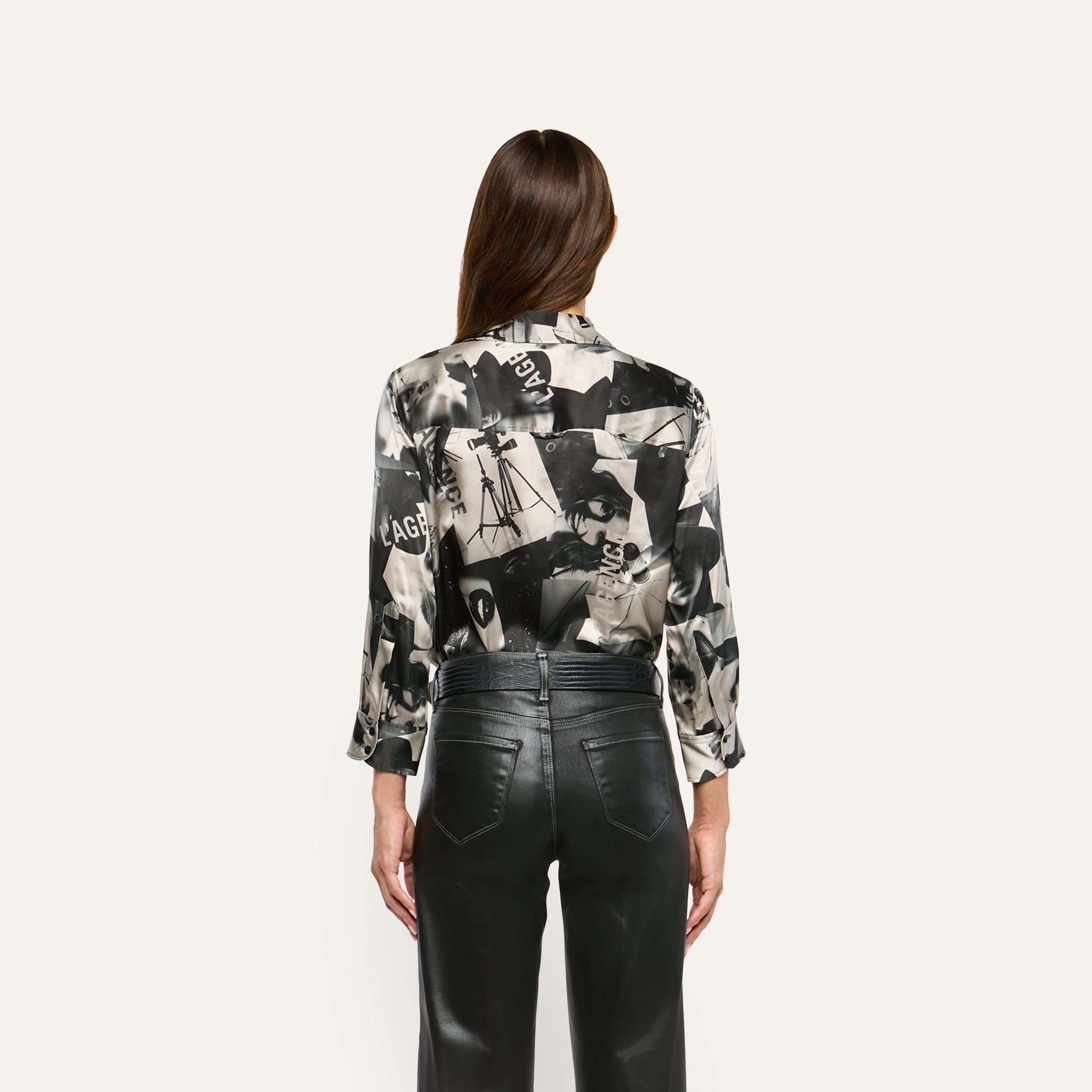 Back view of the Dani Silk Blouse in a black-and-white collage print, tucked into black pants.