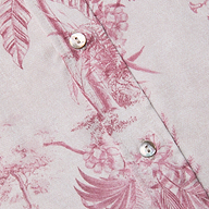 Nahaufnahme der Dani Silk Blouse, einer hellrosa Seidenbluse mit einem dunkelrosa Dschungel-Toile-Druck mit Vögeln und Blättern, zwei weißen Knöpfen und sichtbaren Nähten.