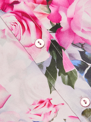 Close-up of the Dani Silk Blouse shows its pink rose print on light silk. Two white buttons on a seam highlight this blouse’s detailed design.