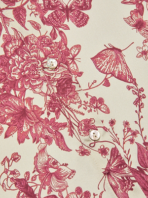 Close-up of cream-colored fabric with an intricate maroon floral butterfly print and two white buttons—perfect for a refined Tyler Silk Blouse.
