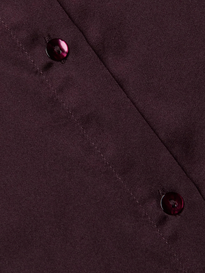 Close-up of the Tyler Silk Blouse by L'AGENCE—a burgundy silk button-down with two maroon buttons along a diagonal seam, suggesting it's part of this elegant long-sleeve shirt.