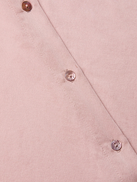 Close-up of the Tyler Silk Blouse in light pink, featuring three shiny round buttons arranged diagonally, showcasing its smooth silk texture and precise stitching along the edge.