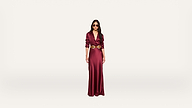 A woman wearing a long, deep red dress with a gold belt and sunglasses stands against a plain white background.