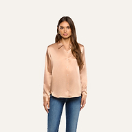 A woman wears a long-sleeved L’AGENCE Tyler Silk Blouse in a light copper tone with blue jeans.