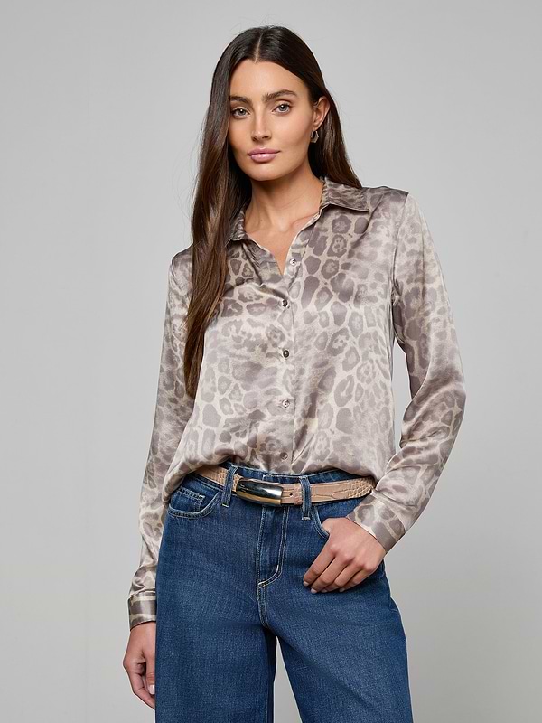 A woman stands with one hand in her pocket against a plain, light background, wearing a long-sleeve animal print blouse tucked into blue jeans and styled with the Marlowe Croc-Embossed Leather Belt.