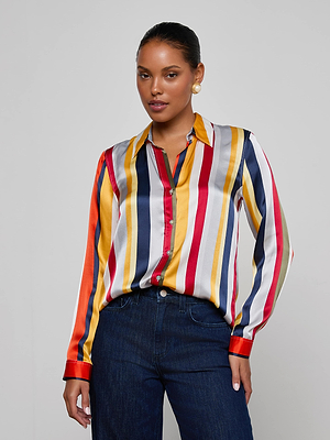 A woman in the Tyler Silk Blouse by L'AGENCE, featuring multi-colored stripes and a button-down design.