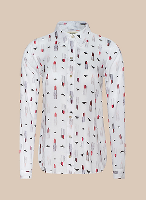 The Holly Blouse is a white, long-sleeve button-down slim fit shirt with a colorful lipstick print in red, pink, and black accents, shown on a plain beige background.