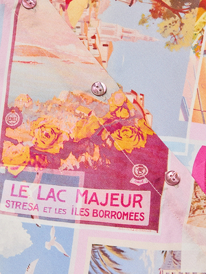 A close-up of the Tyler Silk Blouse by LAGENCE, a colorful travel-themed button-down with yellow flowers, scenic prints, LE LAC MAJEUR STRESA ET LES ÎLES BORROMÉES text, and metal snap closures.