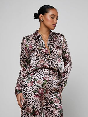 A woman wearing the Tyler Silk Blouse in a rose cheetah print.