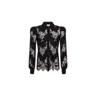 The Jenica Lace Blouse is a black lace blouse with delicate floral patterns, a collared neckline, button-down front, and scalloped hem. This feminine button-up features semi-sheer lace detailing and puffed shoulders, showcased against a plain white background.