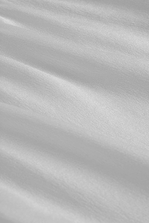 The Calista Silk Camisole features smooth white satin fabric with a subtle sheen, luxurious texture, cowl neck design, and adjustable straps for an elegant look.