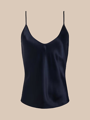The Lexi Silk Camisole in midnight blue features luxe satin charmeuse, thin spaghetti straps, and a V-neckline, displayed against a plain beige background.