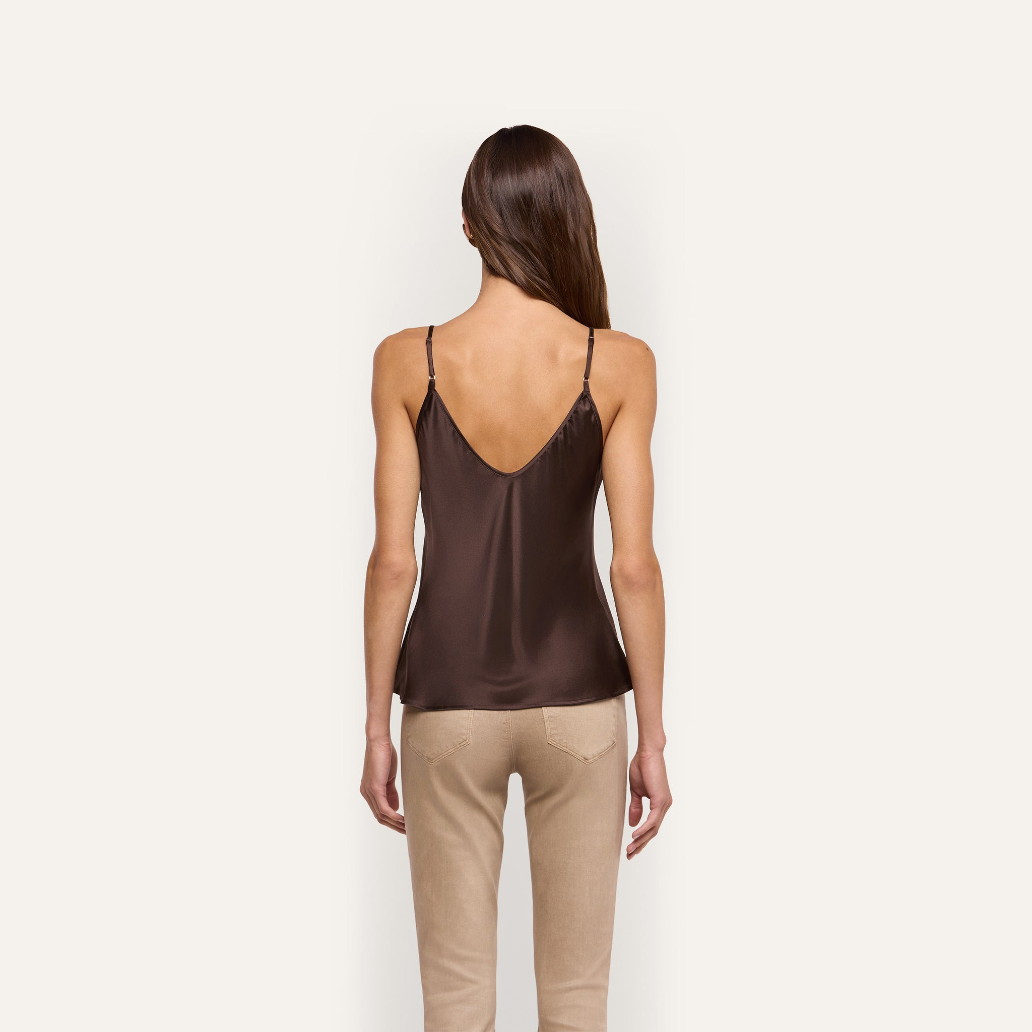 Back view of a person wearing a Lexi Silk Camisole with thin straps and beige trousers.
