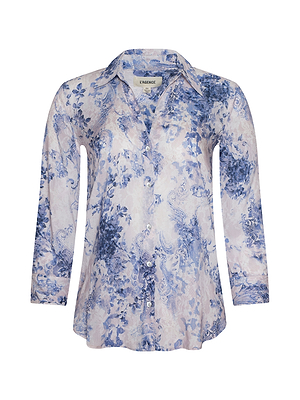 The Camille Blouse is a relaxed-fit, long-sleeve button-down with a collar, showcasing an ivory and blue floral lace print and stylish neckline details.