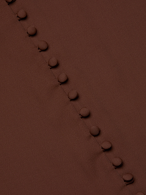 Close-up of the Ava Blouse by L’AGENCE in hot fudge brown, featuring a diagonal row of fabric-covered buttons along a seam for an elegant, vintage-inspired textured design.