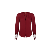 The Ava Blouse is a long-sleeve, deep red, vintage-inspired top featuring fabric-covered buttons down the front and guipure lace detailing at the cuffs, shown against a plain white background.