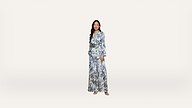 A woman stands against a plain white background, wearing a blue and white floral patterned suit with wide-legged pants and sandals.