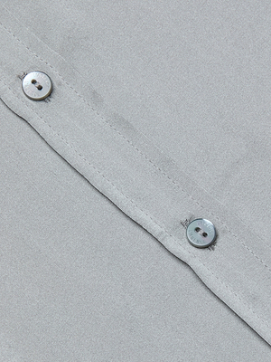 Close-up of the Emmy Sleeveless Silk Blouse in light gray silk charmeuse, featuring two silver buttons along a seam and highlighting luxurious texture and fine stitching—ideal for office to evening style.