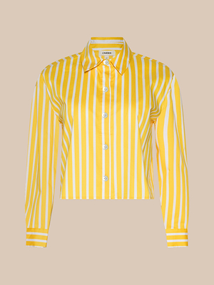 The Cosette Shirt is a long-sleeve, collared button-up made from organic cotton with yellow and white vertical stripes and white buttons, shown on a beige background.
