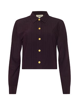 The Cosette Pinstriped Shirt is a long-sleeved, dark purple tailored top made from organic cotton, featuring faint pinstripes, a pointed collar, six gold buttons down the front, and a modern fitted design.