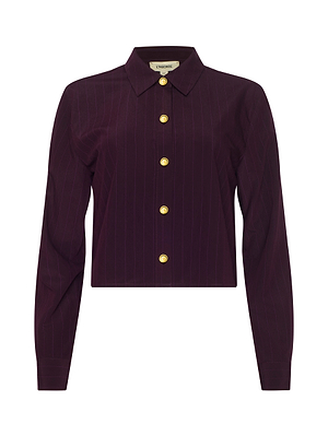 The Cosette Pinstriped Shirt is a long-sleeve, deep purple tailored shirt in organic cotton poplin with subtle pinstripes, gold buttons, and a classic collar, shown on a plain white background.