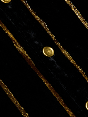 Close-up of the Cosette Velvet Shirt in black, featuring vertical metallic gold stripes and round gold buttons. The fabric’s velvety texture and the shine of both the buttons and stripes are clearly highlighted.