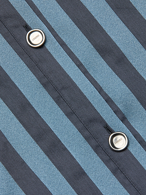 Close-up of the Cosette Satin Shirt, showcasing blue and black diagonal stripes on satin fabric, with two round white buttons sewn onto the material.