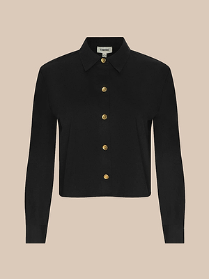 The Cosette Shirt is a black, tailored, cropped shirt with gold buttons down the front, made from organic cotton and shown against a plain beige background.