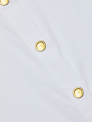 Close-up of the Cosette Shirt, a white poplin design with a diagonal row of gold decorative buttons.