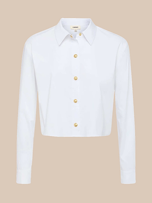 The Cosette Shirt is a white, tailored, long-sleeve button-up with a collared neckline and gold buttons, shown on a plain beige background.