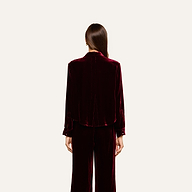 A person with long brown hair, dressed in the Cosette Velvet Shirt in burgundy with matching pants, stands facing away against a plain, light background.