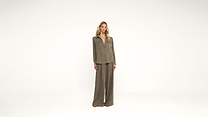 A person stands in the center of a white background wearing an olive green long-sleeved shirt and matching wide-leg pants.