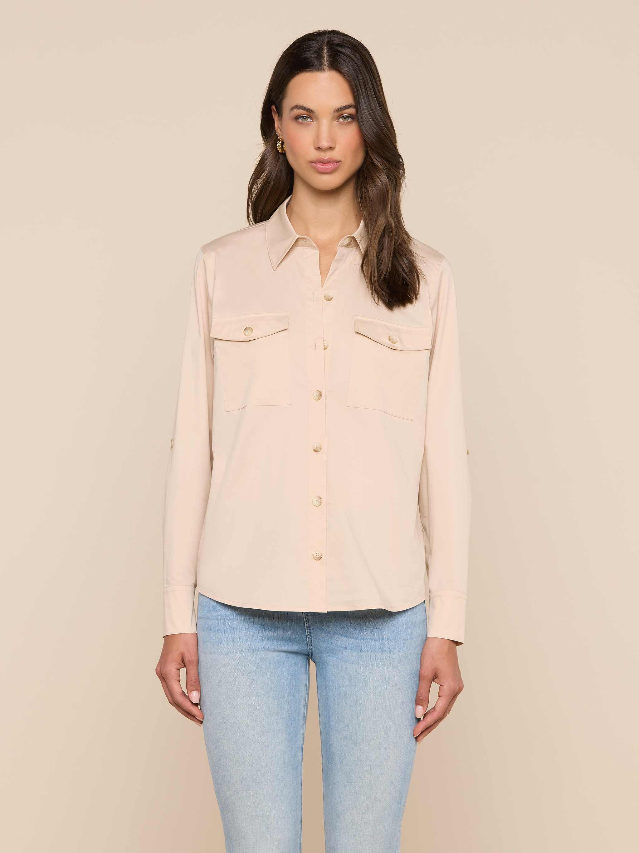 تقف امرأة ذات شعر بني طويل وتعبير وجه محايد، وهي ترتدي قميص «بيرسون بوبلين» Pearson Poplin Shirt، وهو قميص بيج فاتح مستوحى من الملابس العملية، مزود بأزرار وجيوب أمامية، مع بنطال جينز أزرق فاتح، وذلك على خلفية بيج سادة.