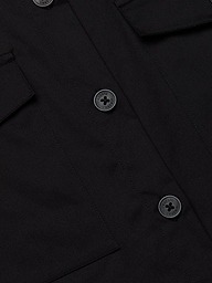 Close-up of the Pearson Poplin Shirt in black, featuring three round buttons and two flap pockets on either side.