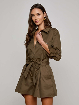 A woman with long brown hair wears the Pearson Blouse by L'AGENCE Sale, a utility-inspired olive-green button-up with long sleeves and flap pockets, standing against a plain light background.