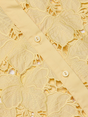 Close-up of the Seychelle Cropped Eyelet Blouse in yellow poplin lace, featuring floral embroidery, a center row of buttons, and large airy eyelets for a delicate look.