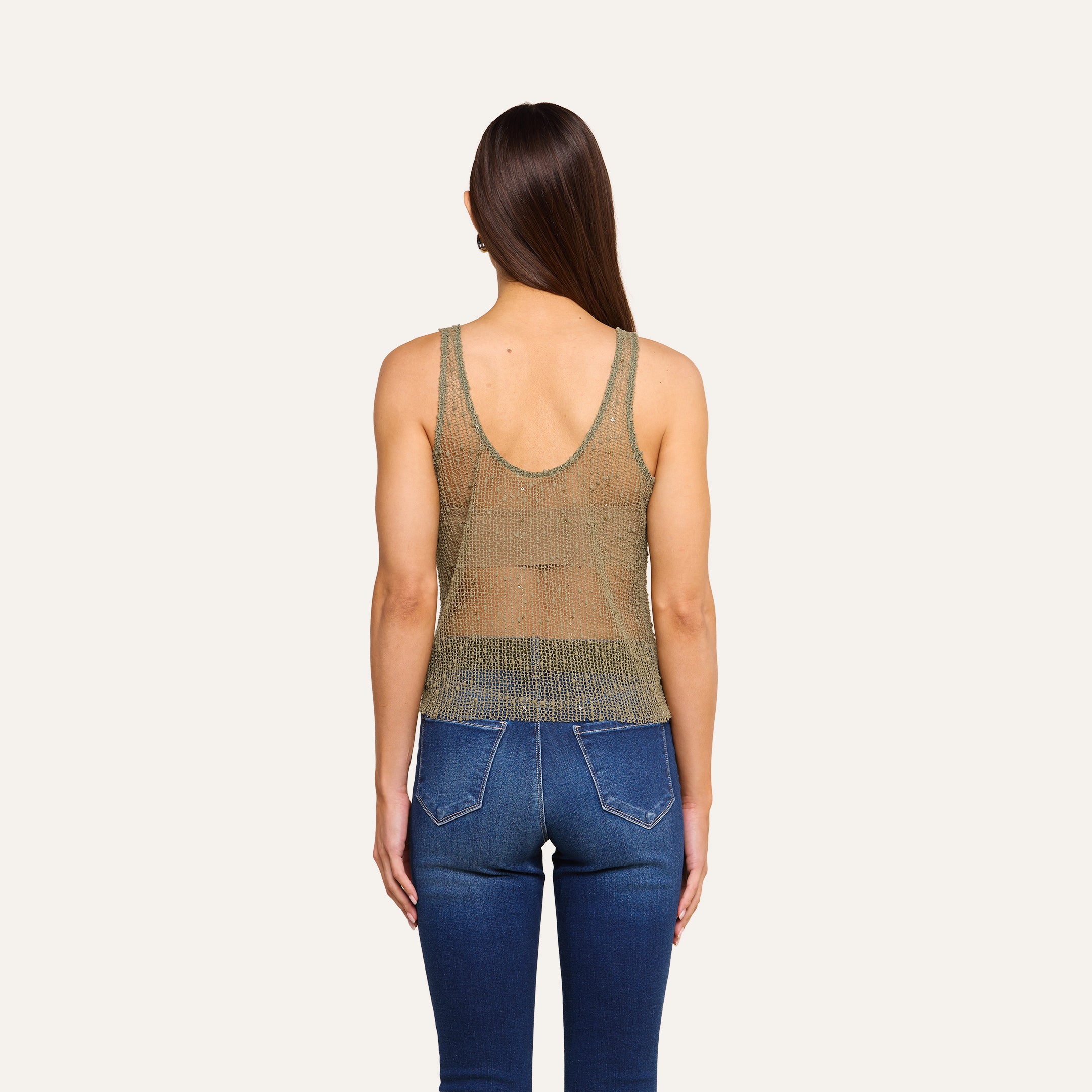 A person with long brown hair is shown from the back, wearing the Zia Tank and blue jeans against a plain beige background.