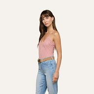 Woman with long brown hair wearing the Gelina Mesh Bodysuit—a pink semi-sheer mesh, sleeveless V-neck design with adjustable straps—paired with light blue jeans and a brown belt, standing against a plain light background and looking slightly to the side.