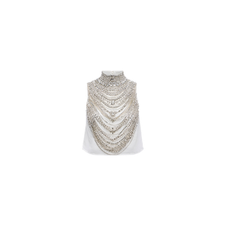 Experience the Yun Draped Crystal Tank: a sleeveless white top featuring a high neckline and cascading layers of silver chains and crystal embellishments that elegantly drape across the front, creating a striking necklace-like effect—an unforgettable statement piece ideal for holiday parties.