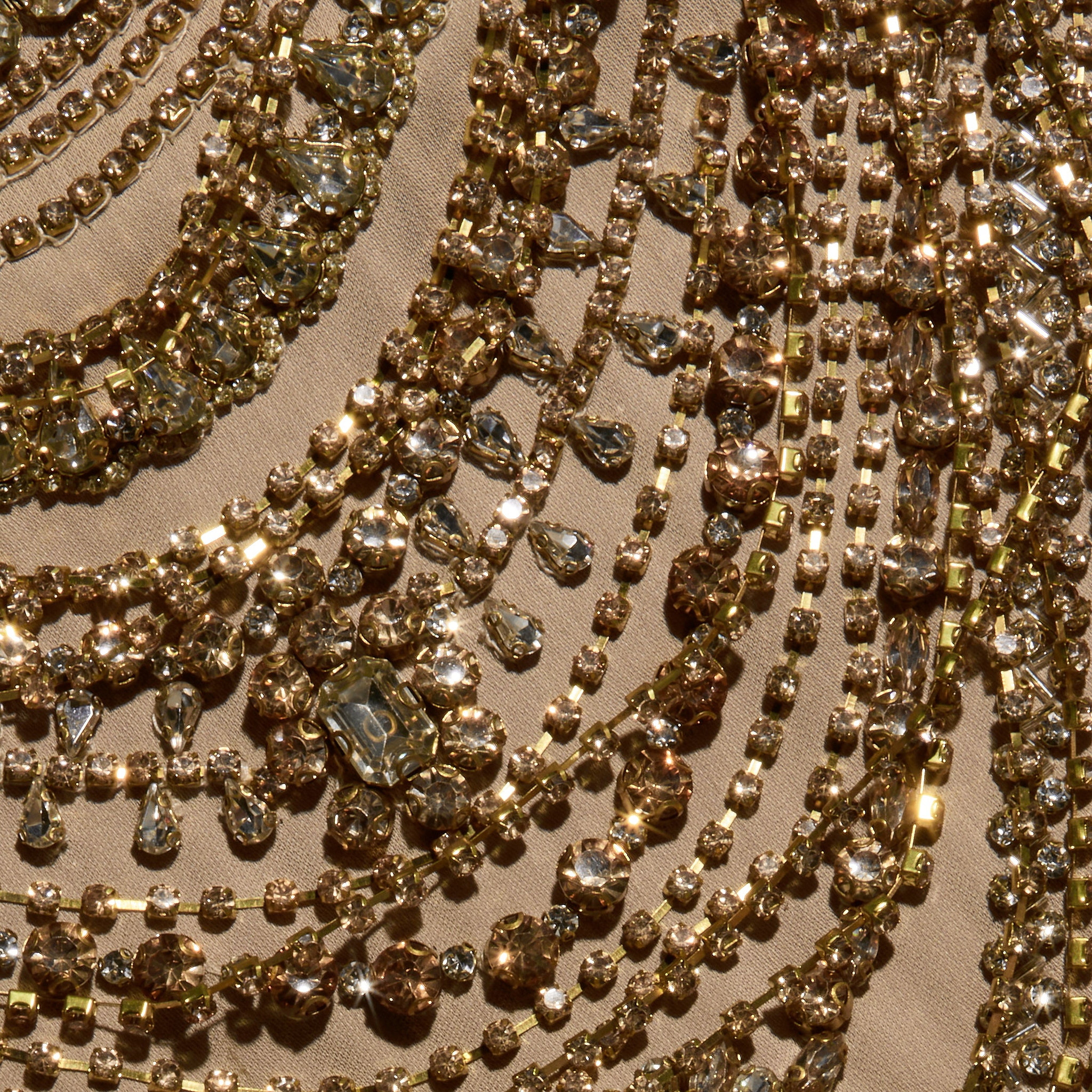 The Yun Crystal Tank features rows of gold-toned chains dripping with faceted crystals arranged in curved patterns on beige fabric.