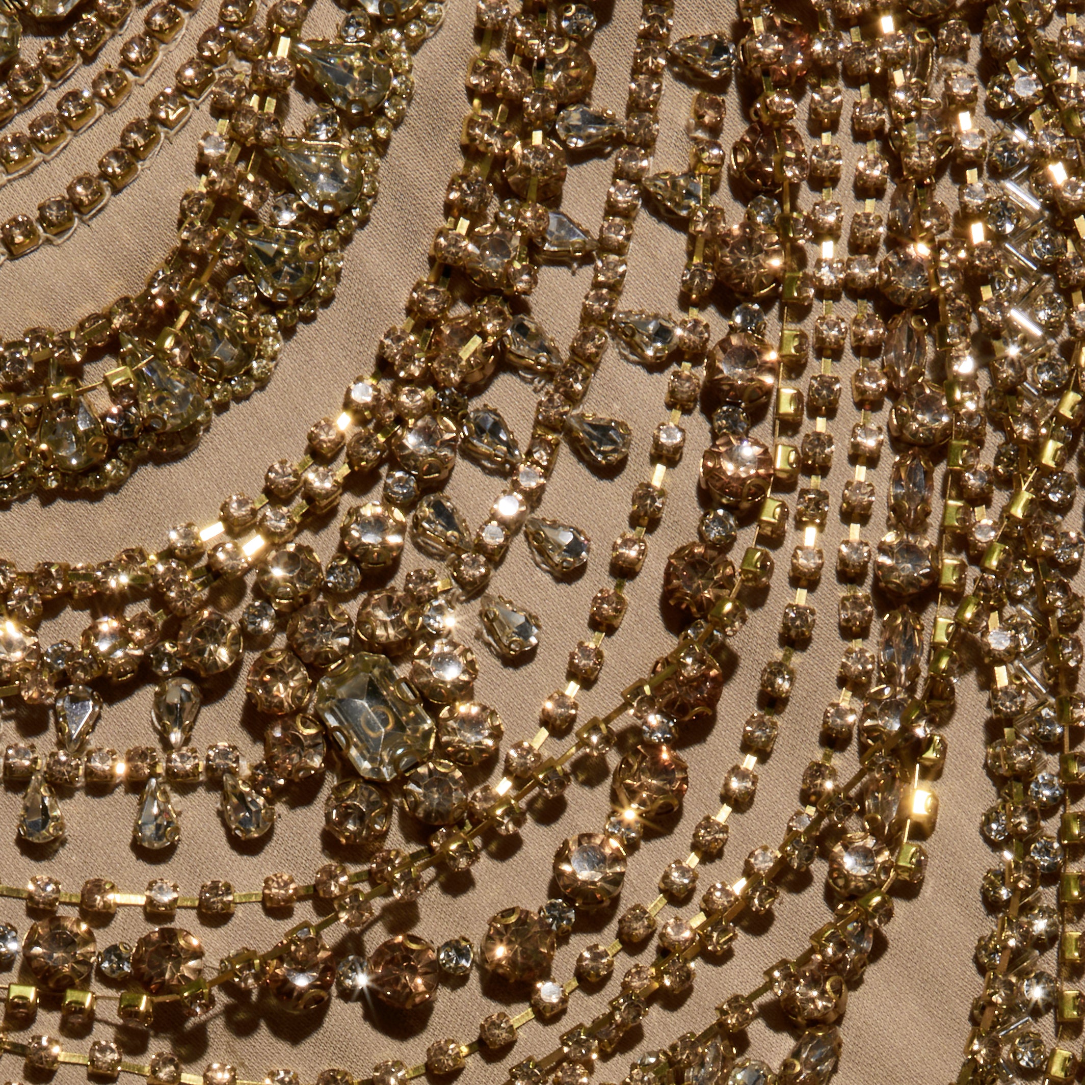 The Yun Crystal Tank features rows of gold-toned chains dripping with faceted crystals arranged in curved patterns on beige fabric.