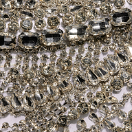 A close-up of numerous sparkling, clear rhinestones of various shapes and sizes clustered together on a reflective surface, evoking the dazzling embellishments of the Yun Draped Crystal Tank—an ideal choice for a festive holiday party.