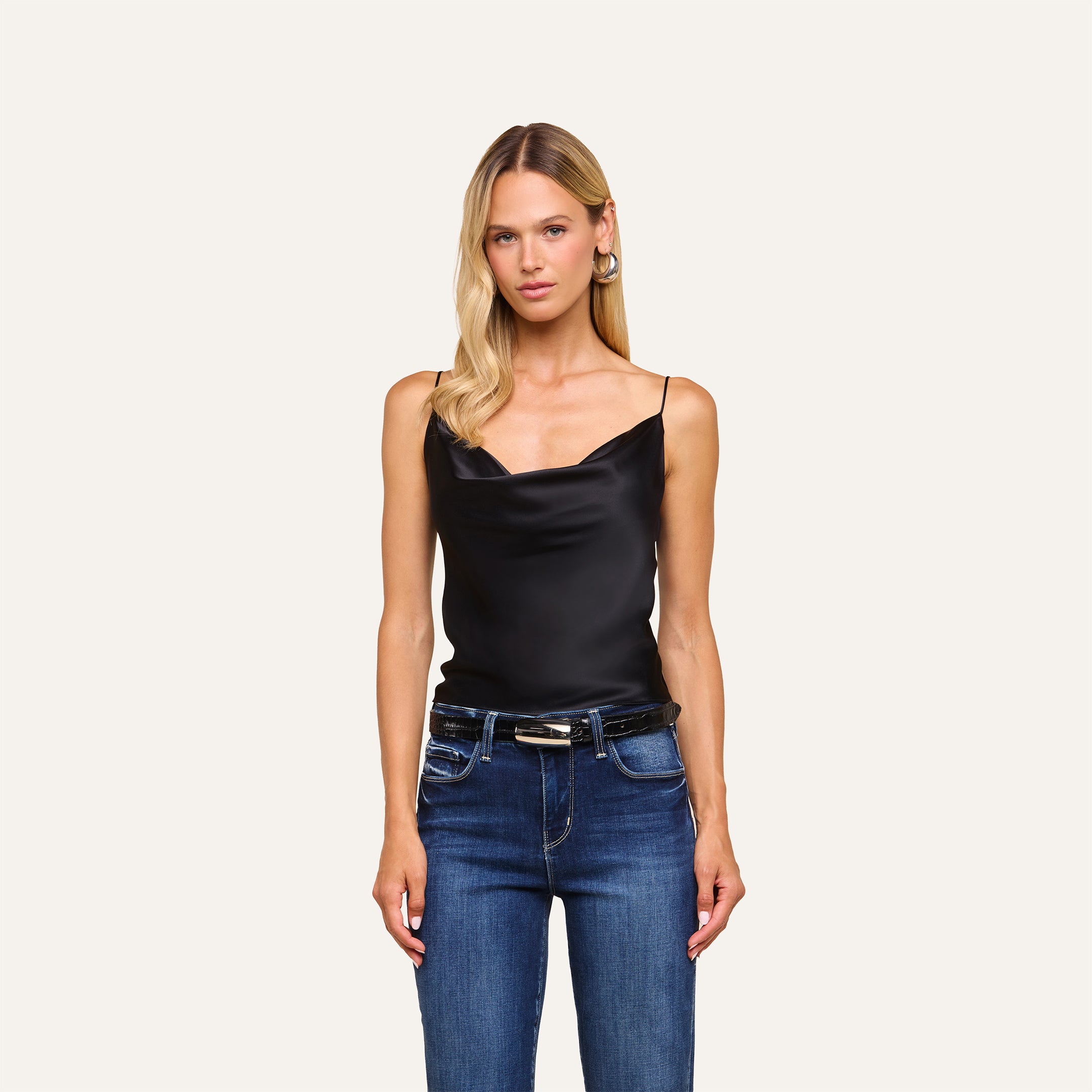 A woman with long blonde hair wears the Calista Silk Camisole in black and blue jeans, standing against a plain light background.