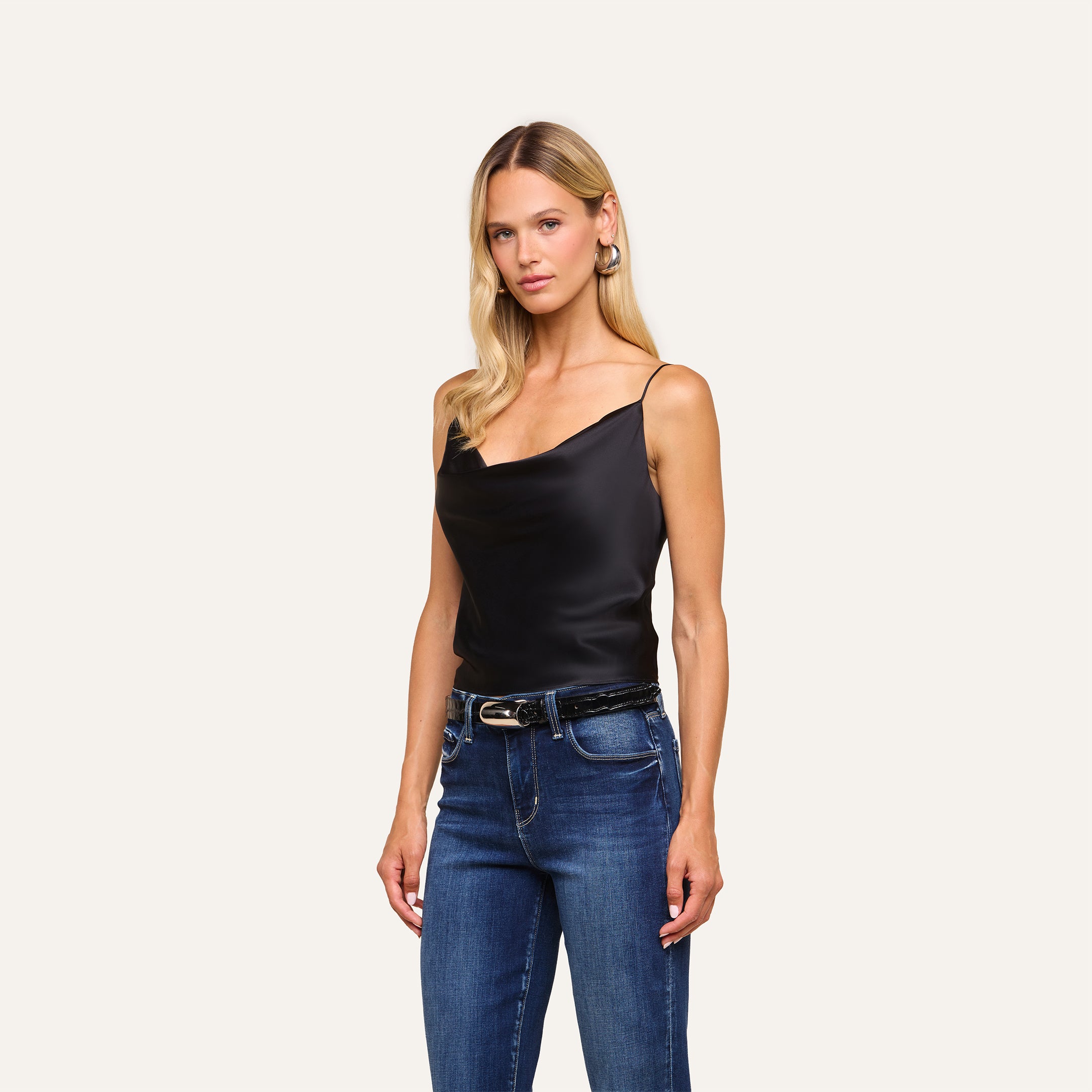 A woman with long blonde hair wears the Calista Silk Camisole in black and blue jeans, standing against a plain light background.
